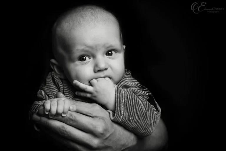 Un bébé qui mange ses doigts sur un fond noir