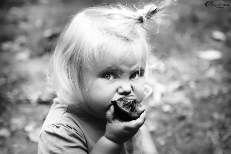 une petite fille qui mange un fruit